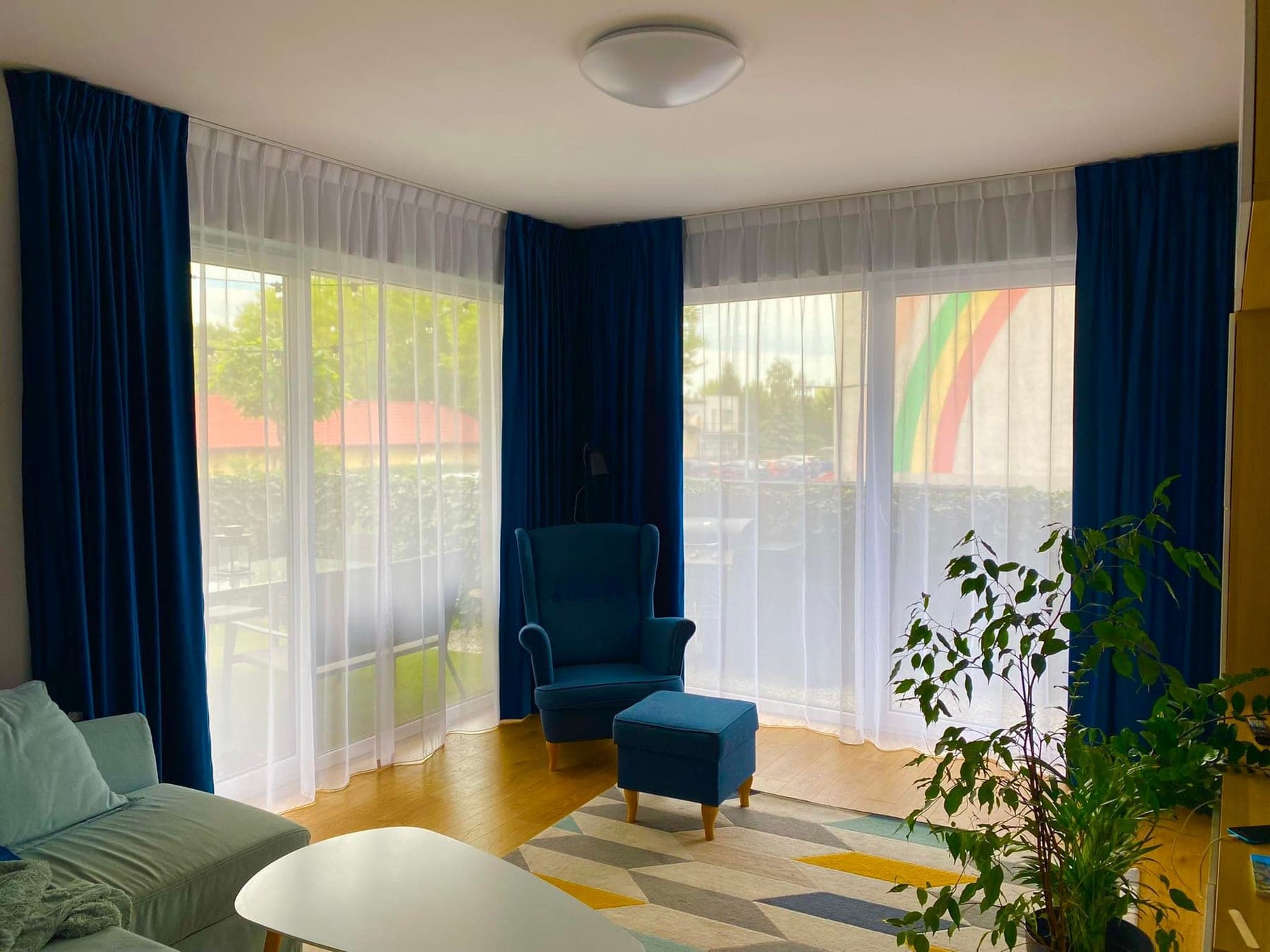 Jasny salon z białymi firanami i granatowymi zasłonami — realizacja Alice Decor